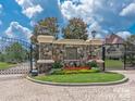 Gated community entrance featuring stone wall, manicured lawn, and decorative landscaping at 1716 Funny Cide Dr, Waxhaw, NC 28173