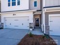 View of the townhome entrance featuring stone accents, a two-car garage, and a welcoming front door at 153 Halite Ln, Waxhaw, NC 28173