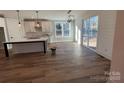 Open kitchen and dining area with hardwood flooring, white cabinets, an island, and modern lighting fixtures at 149 Pinewood St, Troutman, NC 28166