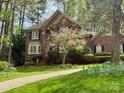 Charming brick home with black shutters, surrounded by mature trees and flowering shrubbery at 21315 Blakely Shores Dr, Cornelius, NC 28031