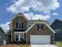 Two-story home showcasing a stone facade, a two-car garage, and manicured landscaping at 1476 Hubert Graham Way, Tega Cay, SC 29708