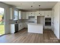 Bright kitchen with white cabinets, an island, stainless steel appliances, and hardwood floors at 1476 Hubert Graham Way, Tega Cay, SC 29708