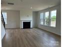 Open living room featuring a fireplace, large windows, and hardwood floors at 1476 Hubert Graham Way, Tega Cay, SC 29708