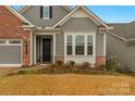 Front entrance of a charming home with gray siding and brick accents at 7014 Jolly Brook Dr, Charlotte, NC 28215