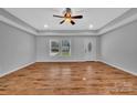 Spacious living room featuring a tray ceiling, ceiling fan and gleaming hardwood floors at 190 Williamson St, Troy, NC 27371