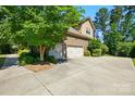 Spacious two-car garage with a large driveway and mature trees offering shade and privacy at 16515 Governors Club Ct, Charlotte, NC 28278