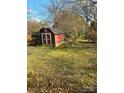Red storage shed in a spacious yard, providing extra storage space and a rustic charm at 116 Lodge Hall Ct, Stony Point, NC 28678