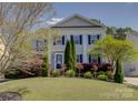 Charming two-story home featuring blue shutters, lush landscaping, and a well-manicured lawn at 10029 Daufuskie Dr, Charlotte, NC 28278