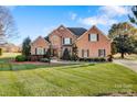 Charming brick home featuring an arched window, black shutters, and green lawn at 2425 Birdie Ne Ln, Conover, NC 28613