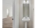 Powder room with pedestal sink and an adjoining room with modern floors at 8205 Stonemere Ln, Charlotte, NC 28215