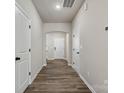 Neutral hallway with wood-look floors, white trim, and multiple doorways at 8205 Stonemere Ln, Charlotte, NC 28215