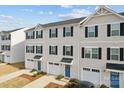 A row of townhomes featuring blue doors, white garages and siding, and neatly trimmed landscaping at 2409 Fathom Way, Charlotte, NC 28269