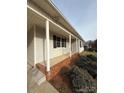 Side view of the house showing a covered porch and brick foundation at 129 Mapleleaf Rd, Statesville, NC 28625