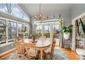Bright dining room featuring large windows, hardwood floors, a wooden table, and unique chandelier, perfect for gatherings at 15215 Timberview Ln, Huntersville, NC 28078