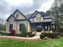 Gorgeous stone and stucco home featuring lush landscaping and a covered front entry at 546 Little Cove Ln, Lake Wylie, SC 29710