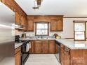 Cozy kitchen featuring granite countertops, wood cabinets, and modern stainless steel appliances at 1805 Tufnell Ct, Charlotte, NC 28262