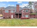 The back of the home showcases a brick exterior, small balcony, and green lawn at 4687 Snow Dr, Harrisburg, NC 28075