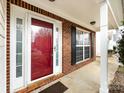 Brick front porch with red door and black shutters at 11813 Fox Glen Rd, Charlotte, NC 28269