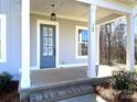 Inviting front porch featuring a blue front door, white columns, and well-maintained landscaping at 148 Dabbling Duck Cir, Mooresville, NC 28117