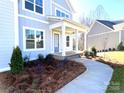 Stylish covered front porch with white pillars, manicured landscaping, and a welcoming entrance at 148 Dabbling Duck Cir, Mooresville, NC 28117