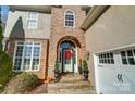 Close-up of a home's stone front entrance with an arched doorway, decorated with a festive holiday wreath at 2315 Smith Harbour Dr, Denver, NC 28037