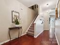 Inviting foyer features hardwood floors, staircase, decorative table with a large mirror, and neutral paint scheme at 7122 Abbotts Glen Dr, Charlotte, NC 28212