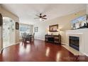 Spacious living room with hardwood floors, a fireplace, ceiling fan, and open access to the dining area at 7122 Abbotts Glen Dr, Charlotte, NC 28212