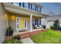 Cozy front porch with seating area, brick accents, and a bright yellow front door at 1345 Shimmer Light Cir, Rock Hill, SC 29732