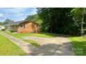 The exterior view of the home features a large driveway leading to a single-story brick home surrounded by mature trees at 2319 Tin Mine Rd, Lincolnton, NC 28092