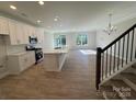 Open kitchen with white cabinets, island, stainless steel appliances, and wood flooring at 4125 Black Ct # 169, Harrisburg, NC 28075