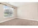 Bright, carpeted bedroom with a large window and neutral walls, offering a blank canvas at 11005 Magna Ln, Indian Trail, NC 28079