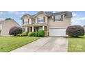Two-story home with a stone facade, well-manicured lawn, and long concrete driveway leading to the garage at 11005 Magna Ln, Indian Trail, NC 28079