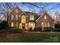 Charming two-story red brick home with a manicured lawn, beautiful landscaping, and elegant architectural details at 13101 Whisper Creek Dr, Charlotte, NC 28277