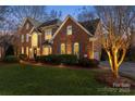 Elegant brick home featuring lush landscaping, arched windows, and warm exterior lighting at 13101 Whisper Creek Dr, Charlotte, NC 28277