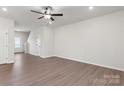 A large open-concept living room with wood flooring, a ceiling fan, and bright, neutral walls at 3250 Maple Ridge Dr, Gastonia, NC 28052