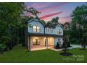 Two-story house with gray siding, a covered porch, and landscaping at dusk at 13114 Blacksmith Ct, Matthews, NC 28105