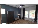 A naturally lit room with light hardwood floors, paneled accent wall, dark curtains, and ceiling fan at 327 Coxe Ave, Charlotte, NC 28208