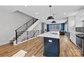 Open-concept kitchen with modern island, stainless steel appliances, and an open staircase at 327 Coxe Ave, Charlotte, NC 28208