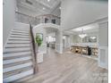 A grand foyer features an open staircase, wood floors, a soaring ceiling, and an adjacent dining room and kitchen at 1312 Pleasant Plains Rd, Matthews, NC 28105