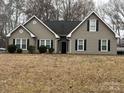 Gray house with black shutters, a black roof, and a well-maintained lawn at 13410 Old Camden Rd, Midland, NC 28107