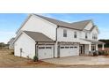 Side view of a two-story home, featuring a stone and white shingle facade and two-car garage at 13019 Arnold Palmer Cir # 832, Lancaster, SC 29720