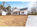 A beautiful white home with wood accents and a well manicured front yard and a view of the driveway at 1306 Eddie St, Gastonia, NC 28054