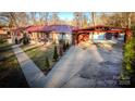 Ranch home with a large driveway and carport, surrounded by trees at 152 Woodlynn Dr, Charlotte, NC 28214