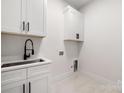 Bright laundry room with white cabinets and a modern sink at 10614 Arlington Church Rd, Charlotte, NC 28227