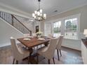 Bright dining room featuring hardwood floors, a chandelier, and large windows creating an inviting and cozy atmosphere at 1304 Pleasant Plains Rd, Matthews, NC 28105