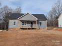 New construction home featuring gray siding, covered front porch, and unfinished landscaping under a cloudy sky at 524 Waco Rd, Kings Mountain, NC 28086