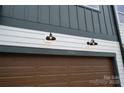 Close up of modern townhouse exterior featuring a brown garage door and black outdoor lighting at 7932 Cedarsmith Ct, Charlotte, NC 28217