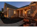 Evening view of brick home with landscaped yard and walkway at 1108 Butterburr Dr, Matthews, NC 28104