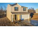 Two-story house with beige vinyl siding, white garage door, and a landscaped yard at 136 Jo Creek Ln, Harmony, NC 28634