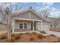 Inviting home featuring a covered porch with stone accents, attached garage, and landscaped front yard at 14509 Batteliere Dr, Charlotte, NC 28278